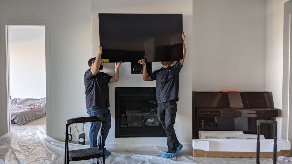 Expert TV installer mounting a large screen over a fireplace